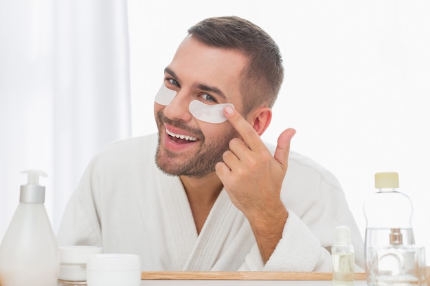 Tão bonito. homem simpático e feliz olhando no espelho enquanto usava tapa-olhos