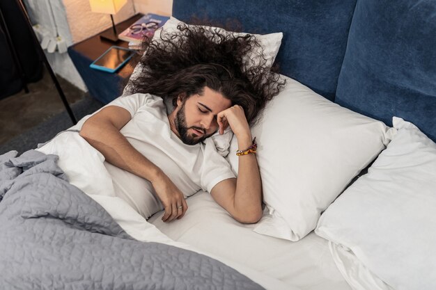 Tão cansado. Belo homem de cabelos compridos tentando dormir enquanto está muito cansado