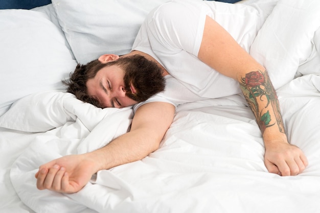 Tão cansado. homem sonolento brutal no quarto. macho maduro com barba de pijama na cama. energia e cansaço. adormecido e acordado. homem barbudo hipster dormir de manhã. ele está muito cansado hoje.