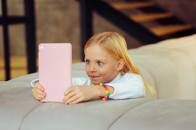 Tão interessante. Menina atenta expressando positividade enquanto olha para a tela de seu gadget