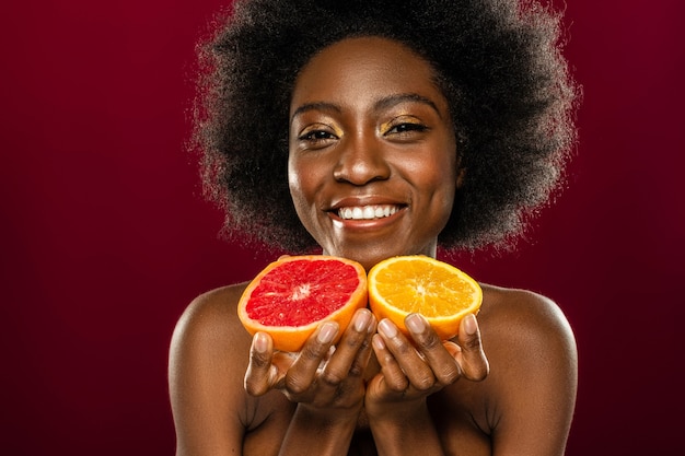 Tão suculento. Mulher simpática e encantada sorrindo enquanto lhe oferece frutas frescas