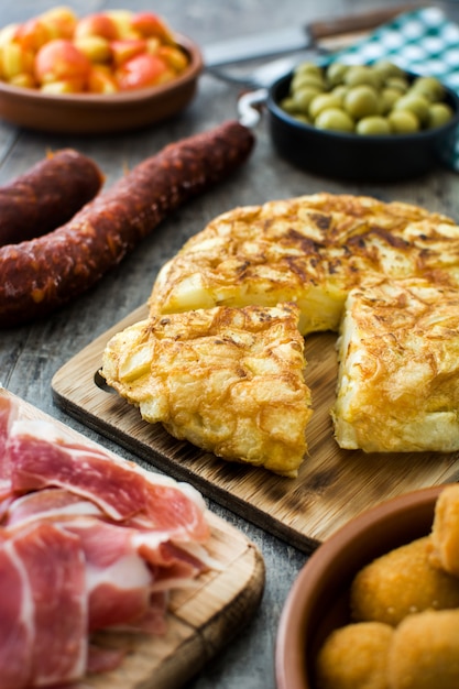 Tapas españolas tradicionales. Croquetas, aceitunas, tortilla, jamón y patatas bravas en mesa de madera