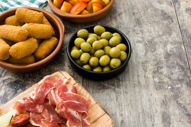 Tapas españolas tradicionales. Croquetas, aceitunas, tortilla, jamón y patatas bravas en mesa de madera