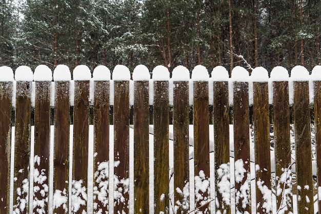 Tapas de nieve encima de una valla de madera.