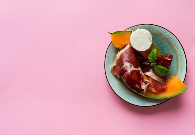 Foto tapas tradicionales españolas jamón ibérico con queso de cabra, melón y miel sobre fondo rústico. vista superior. lay flat.