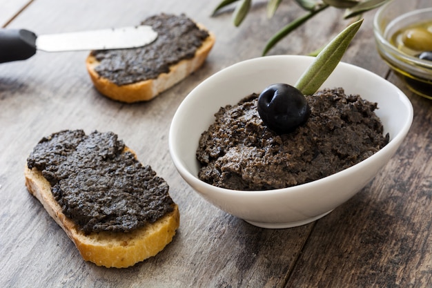 Tapenade de aceituna negra con anchoas, ajo y aceite de oliva en mesa de madera