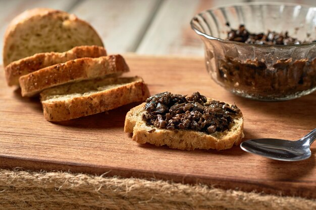 Tapenade de aceitunas negras en un tazón con cuchara y pan