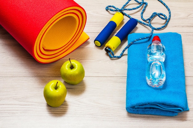 Tapete de ioga e diferentes ferramentas para fitness no chão da sala