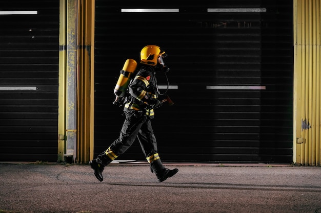 Tapferer Feuerwehrmann in Schutzuniform mit voller Ausrüstung, um sich um das Feuer zu kümmern.