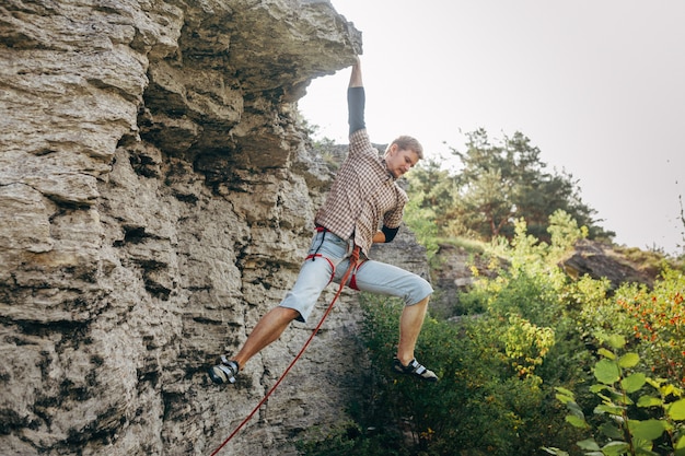 Tapferer junger Mann klettert die Klippe