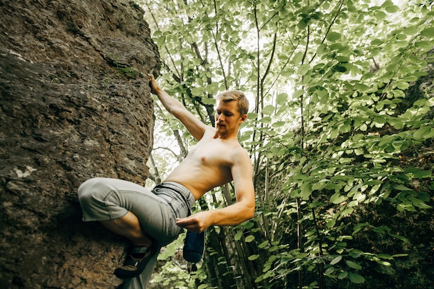 Tapferer junger Mann klettert die Klippe