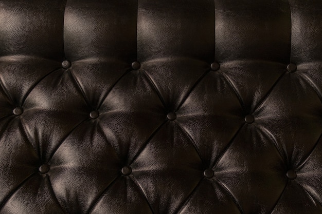 Tapicería de cuero en el sofá con luces y sombras, primer plano.