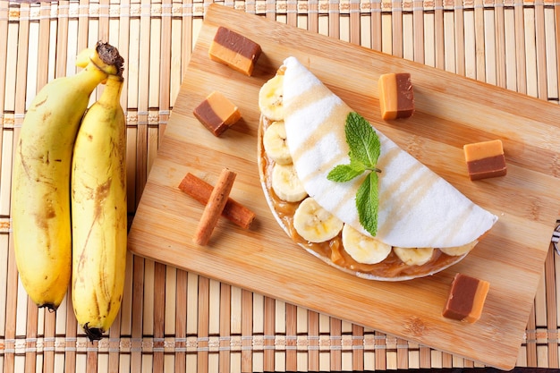 Foto tapioca casera o beiju rellena de plátano y leche condensada o caramelo malteado sobre mesa rústica de madera