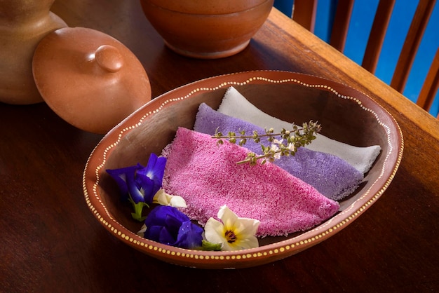 Tapioca Coloridas tapiocas brasileñas servidas en cuencos de arcilla con flores silvestres para el desayuno