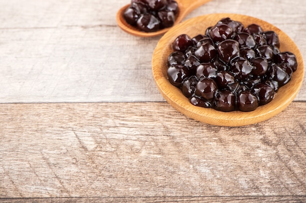 Tapioca Pearl, cobertura de burbujas para té u otra bebida, en una taza, colóquela sobre la mesa de madera. Copia espacio