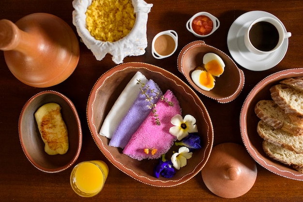 Tapioka Bunte brasilianische Tapiokas, serviert in Tonschalen mit Wildblumen zum Frühstück