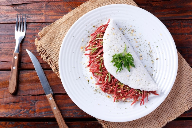 Tapioka oder Beiju gefüllt mit getrocknetem Fleisch Ruckfleisch auf einem rustikalen Holztisch Typisch brasilianisches Essen