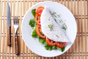 Tapioka oder beiju mit gemüse tomaten-rucola in weißer platte über rustikalem holztisch veganes fitness-essen glutenfrei