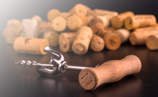 Los tapones de vino y el sacacorchos en la mesa de madera negra a la suave luz del sol