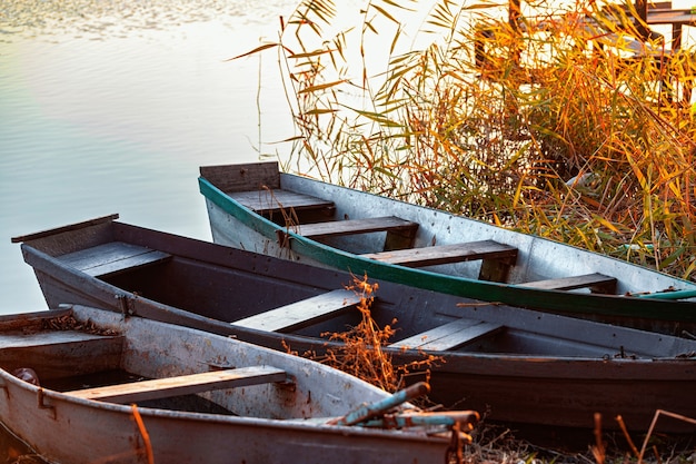 Tarde de otoño en la orilla de un río desierto con tres barcos de pesca en la orilla nadie