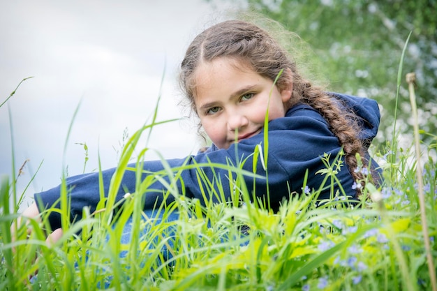 En la tarde de verano en la orilla del río, una niña se sienta en la hierba alta