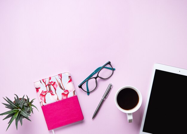 Tarea. Business flat lay con taza de café, nota, lápiz, anteojos, tableta y sicculent sobre fondo rosa