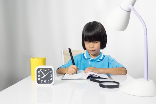 Tarea linda de la escritura del niño de la muchacha en el escritorio