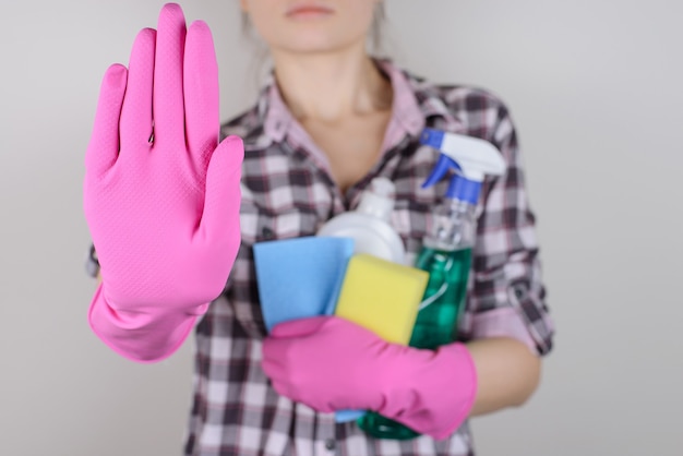 Las tareas de la cámara limpian los productos químicos claros desinfectan el concepto de persona de la gente del trabajador del trabajo de rutina. Cerrar foto de dama segura seria haciendo señal de stop mostrando mano aislada sobre fondo gris espacio de copia