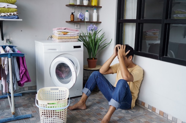 Tareas del hogar. Destacó el hombre asiático lavando ropa en casa cargando ropa en la lavadora
