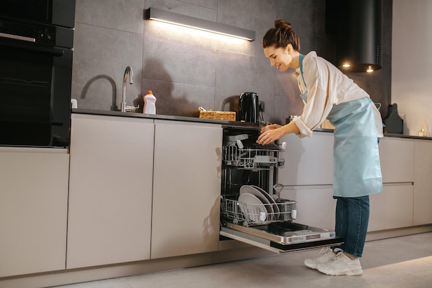 Tareas del hogar. Mujer joven en la cocina que parece ocupada mientras lava los platos