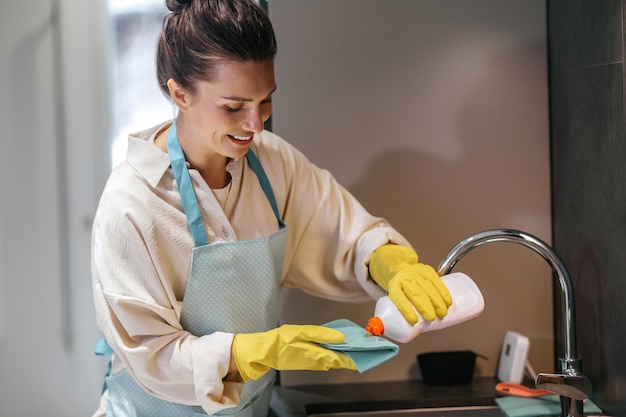 Tareas del hogar. Mujer sonriente en guantes amarillos haciendo tareas domésticas