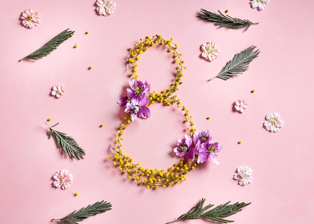 Foto tarjeta del 8 de marzo sobre fondo rosa hermosas flores de mimosa amarillas y hojas verdes concepto del día internacional de la mujer