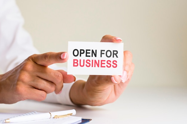 tarjeta de 'abierto para negocios' en manos de la mujer. Negocios, Ética, Publicidad, Marketing.