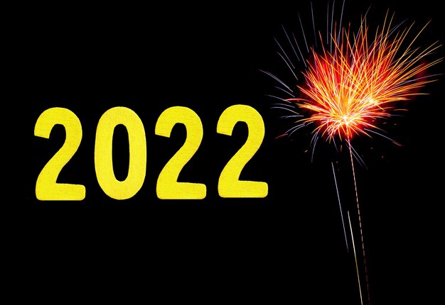 Tarjeta de año nuevo para 2022 con dígitos de oro sobre un fondo de fuegos artificiales.