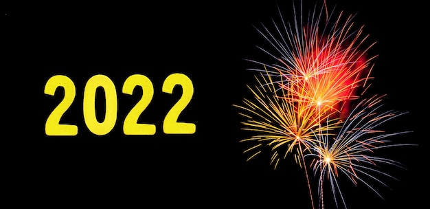 Tarjeta de año nuevo para 2022 con dígitos de oro sobre un fondo de fuegos artificiales.