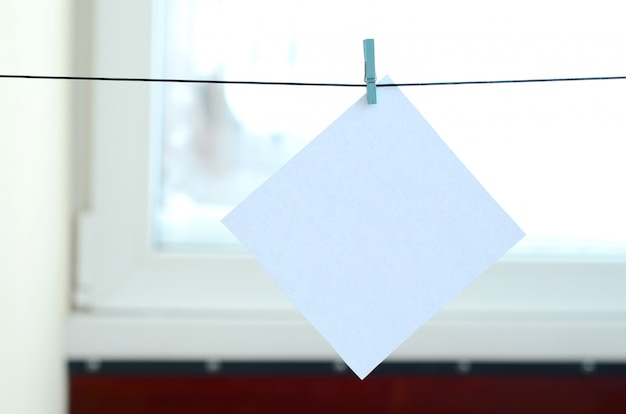 Tarjeta blanca en blanco en la cuerda, fondo de vidrio de ventana