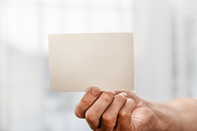 Una tarjeta blanca en blanco en la mano de un hombre sobre un fondo blanco Un espacio en blanco para una inscripción de diseño