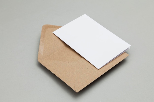 Tarjeta blanca en blanco con maqueta de plantilla de sobre de papel marrón kraft
