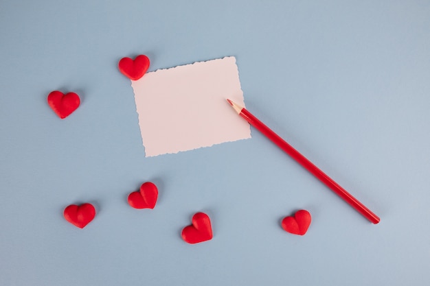 tarjeta en blanco blanca corazón rojo y lápiz rojo sobre tabla azul