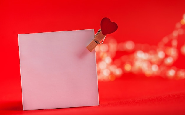 Tarjeta en blanco con un corazón para el texto sobre un fondo rojo concepto de nota de amor del día de San Valentín