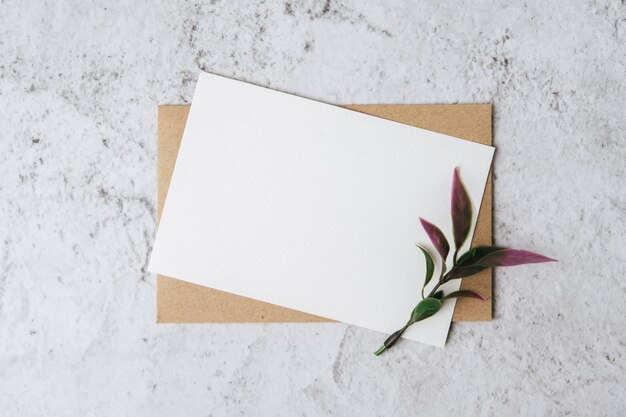 Una tarjeta en blanco con sobre y flor se coloca sobre un fondo blanco