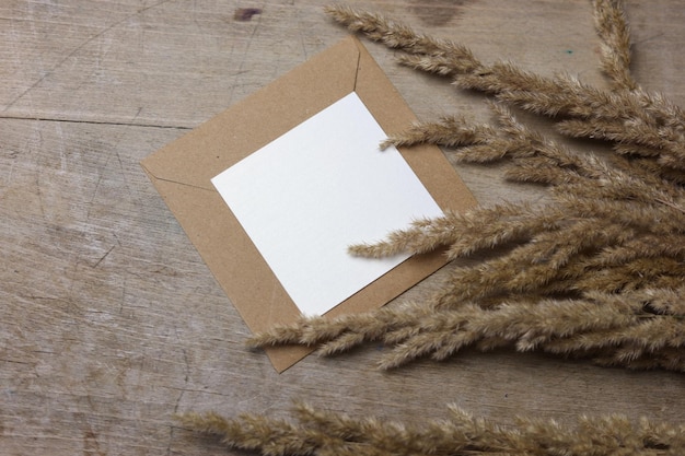 una tarjeta en blanco en un sobre marrón con una hierba decorativa seca en el costado