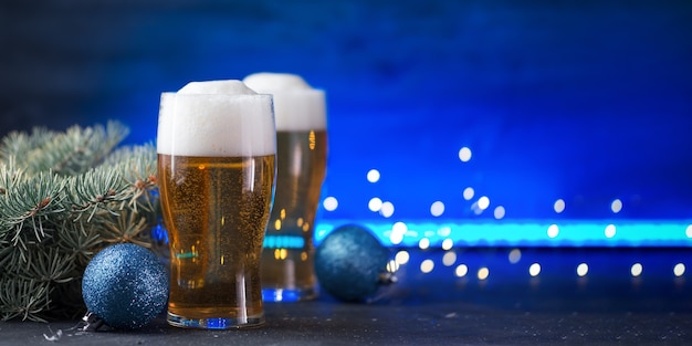 Tarjeta de brindis de Navidad, dos vasos de cerveza ligera sobre un fondo de neón de color con guirnaldas y espacio de copia