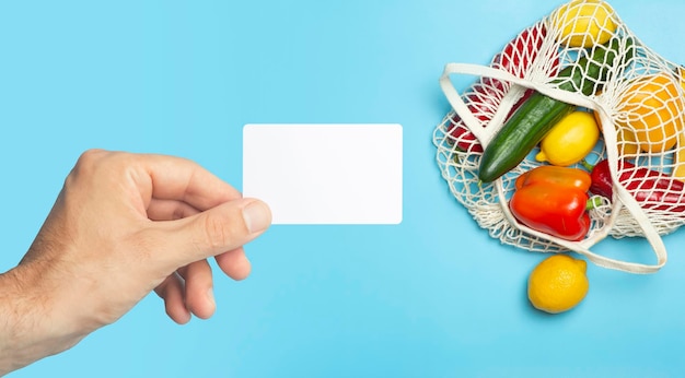 Tarjeta de comestibles de plástico vacía en la mano en la tarjeta de comestibles de fondo de alimentos de supermercado