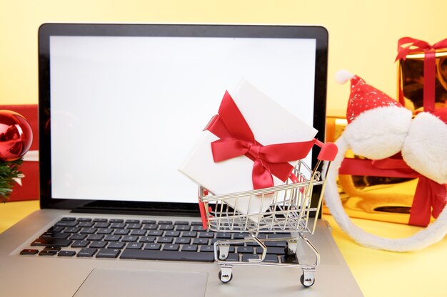 Tarjeta de crédito y computadora portátil con cajas y regalos de Navidad