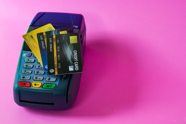 Tarjeta de crédito y escáner de tarjeta de crédito sobre un fondo rosa