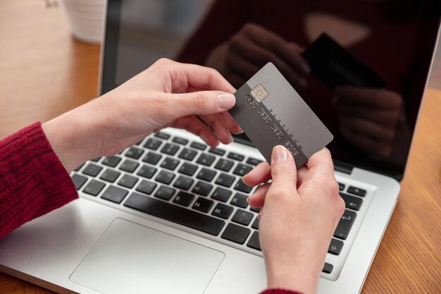 Tarjeta de crédito en mano y computadora portátil mesa de madera vista de cerca Compras en línea