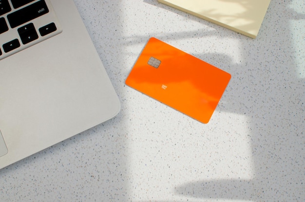 Tarjeta de crédito de plástico con chip visible encima de una mesa con luces suaves y sombras en la superficie.