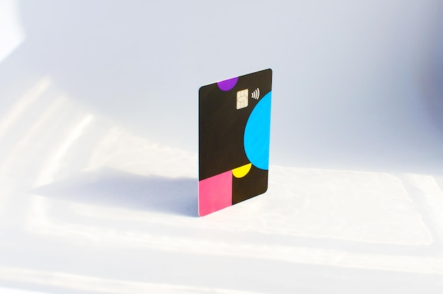 Tarjeta de crédito de plástico con chip visible encima de una mesa con luces suaves y sombras en la superficie.