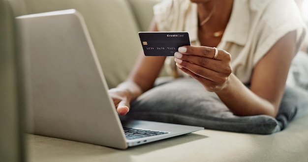 Tarjeta de crédito portátil y manos de mujer compras en línea para ofertas de descuento compra financiera o elección de comercio electrónico débito pago fácil y primer plano cliente escribiendo contraseña bancaria en el sofá del salón de casa